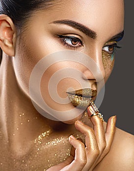 Fashion art makeup. Portrait of beauty woman with golden skin. Shiny professional makeup