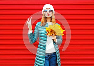 Fashion autumn woman holds yellow maple leaves, blows red lips