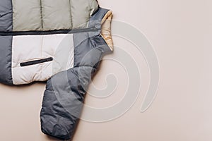 Fashion baby colorblock puffer jacket on grey background. Top view, flat lay. Newborn beige clothes outfit. Winter