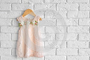 Fashion baby girl dress hanging on white brick wall