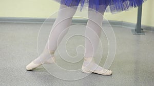 Fashion ballerina dancing in a dark ballet class. The girl performs dance steps in a stage costume. Slow motion.