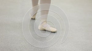 Fashion ballerina dancing in a dark ballet class. The girl performs dance steps in a stage costume. Slow motion.