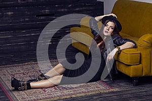 Fashion beautiful middle eastern model with hipster style is posing on carpet and yellow sofa.