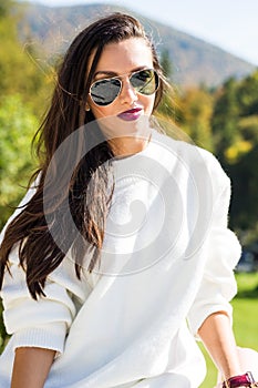 Fashion beautiful woman portrait wearing sunglasses, white sweater and green skirt