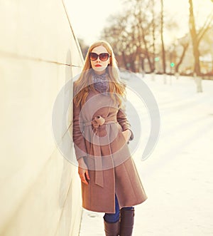 Fashion beautiful young blonde woman wearing coat jacket and sunglasses in winter city
