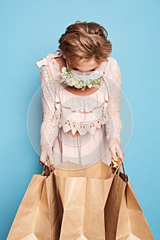 Fashion beauty cool young girl in medical mask designed with natural flowers standing with shopping bags in summer dress