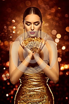 Fashion Beauty Model holding Golden Jewelry Flowers in Hands. Woman Face Hand Skin Care and Cosmetic over Shining Lights