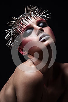 Fashion beauty model with metallic headwear and shiny silver red makeup and blue eyes and red eyebrows on black background