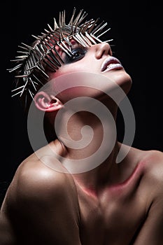 Fashion beauty model with metallic headwear and shiny silver red makeup and blue eyes and red eyebrows on black background