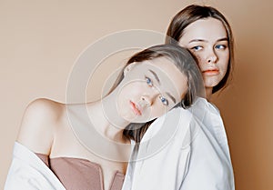 Fashion beauty models two sisters twins beautiful nude girls looking at the camera on beige background