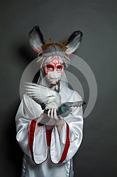Fashion beauty portrait of perfect young woman rabbit with pigeon bird standing on black background. Halloween makeup and costume