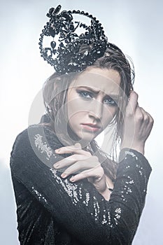 Fashion beauty portrait of young beautiful young woman with makeup and freckles on her face with black crown on her head