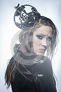 Fashion beauty portrait of young beautiful young woman with makeup and freckles on her face with black crown on her head