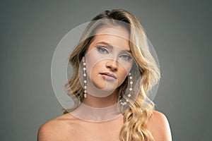 Fashion beauty portrait of young caucasian woman with pearls jewelry and elegant hairstyle. Blonde girl with long wavy hair
