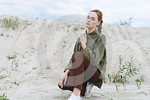 Fashion beauty portrait of young woman in green organic velvet shirt on the desert background