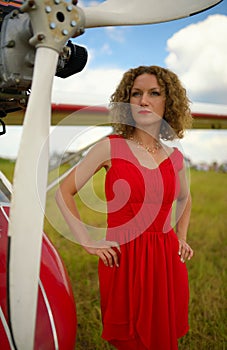 Fashion beautyful woman in red dress nearby ultralight plane