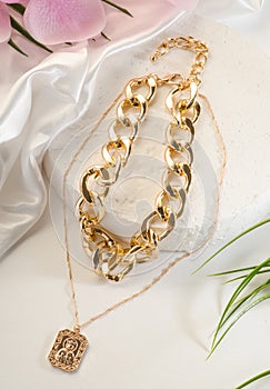 Fashion bijouterie - large and thin double gold chain with a pendant on a white stand
