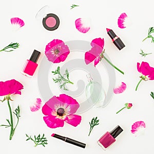 Fashion blogger desk with cosmetics - lipstick, eye shadows, nail polish and pink flowers on white background. Flat lay, top view.