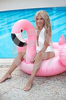 Fashion blond model woman in white bikini posing on Pink in