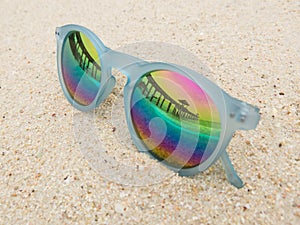 Fashion blue frame sunglasses on sandy sea beach with mirror