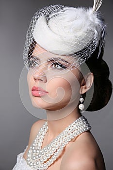 Fashion Brunette Retro Model Portrait. Pearls Jewelry and Hairstyle. Elegant lady Isolated on studio gray background.