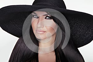 Fashion brunette woman model posing in black hat isolated on white background