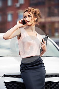 Fashion business woman calling on mobile phone beside a car