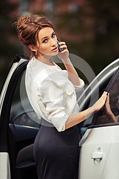 Fashion business woman calling on mobile phone beside a car