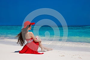 Fashion carefree woman in hat enjoying exotic sea, brunette relax on tropical beach at summer holiday. Attractive girl in red