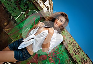 Fashion Caucasian model posing outdoor in front of an old boat