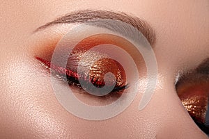 Fashion Celebrate Makeup with Red Liner, Gold Shadows, Glowy Clean Skin, perfect Shapes of Brows. Macro of Female Eye