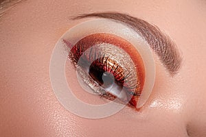 Fashion Celebrate Makeup with Red Liner, Gold Shadows, Glowy Clean Skin, perfect Shapes of Brows. Macro of Female Eye