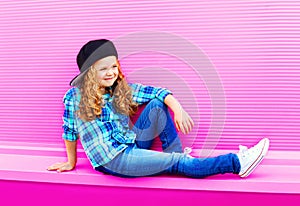 Fashion child girl in baseball cap with curly hair on colorful pink wall