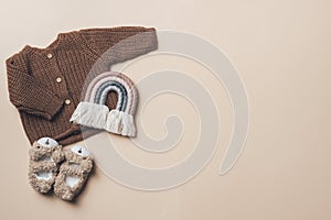 Fashion children's clothing, shoes. Set of knitted baby clothes. Newborn brown jumper, boots, rainbow toy on grey