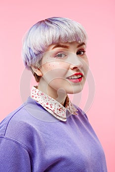 Fashion close-up portrait of smiling beautiful dollish girl with short light violet hair wearing lilac sweater over pink