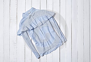 Fashion clothes. Blue and white striped shirt with flounce on white wooden floor planks photo