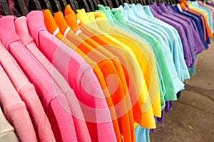 Fashion clothes on clothing rack - bright colorful closet. Close-up of rainbow color choice of trendy female wear