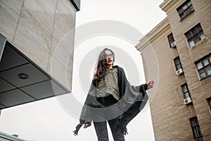 Fashion consept: beatiful young girl with long hair, glasses, red lips standing near modern wall wearing in green suit and grey je