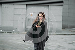 Fashion consept: beatiful young girl with long hair, glasses, red lips standing near modern wall wearing in green suit and grey je