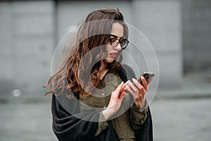 Fashion consept: beatiful young girl with long hair, glasses, red lips standing near modern wall wearing in green suit and grey je