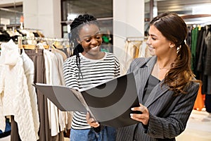 Fashion Consultant Showing a Folder with a Clothing Catalog to a Happy Client photo