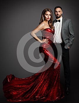 Fashion Couple. Beauty Woman in Red Dress and Handsome Man in Classic Suit with Bow Tie. Elegant Lady in Luxury Gown and Gentlemen