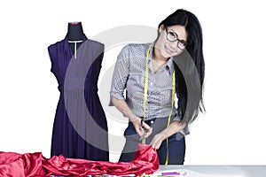 Fashion designer cutting a fabric on studio