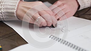 Fashion designer drawing model for clothes sketch. Hand of female tailor drawing pattern at paper in her studio.