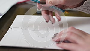 Fashion designer drawing model for clothes sketch. Hand of female tailor drawing pattern at paper in her studio.