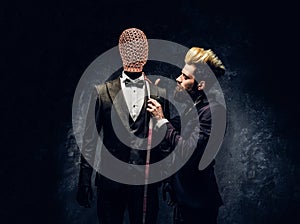 A fashion designer with expressive style working with custom made men`s suit in a dark tailor studio