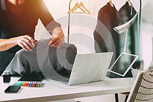 Fashion designer holding shirt and using laptop with digital tab