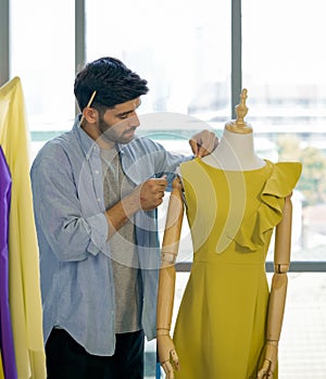 Fashion designer room. The men`s dressmaker using tape measure measuring the shoulder size of dress on the mannequin