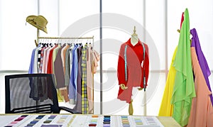 Fashion designer room, The red shirt and tape measure are on the mannequin. A clothes rack with colorful fabrics in front of the