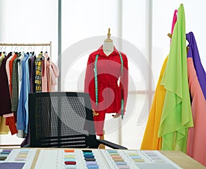 Fashion designer room, The red shirt and tape measure are on the mannequin. A clothes rack with colorful fabrics in front of the